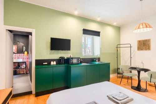 Modern Superior Double Room at Suite Maradona Naples with green kitchenette, wall-mounted TV, and wooden flooring