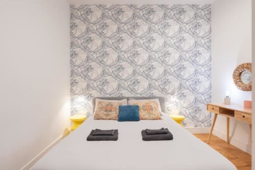 Modern double bedroom at Suite Maradona B&B in Naples with patterned headboard, blue accent pillow, wooden desk, and wooden