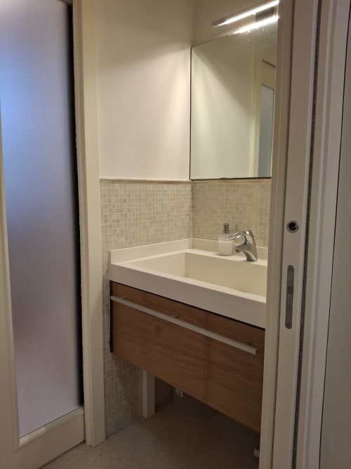 Lavabo moderno con bacino bianco, mobile in legno e mobile a specchio presso l'hotel Prince Garda a Serniga