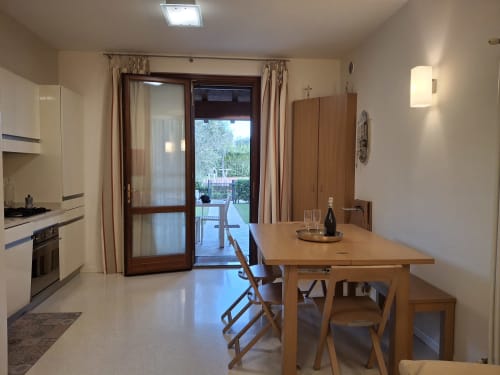 Cucina e zona pranzo moderna dell'hotel Prince Garda a Serniga, con tavolo in legno, mobili color crema e vista giardino