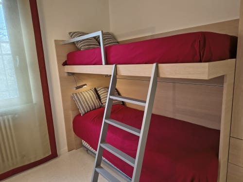 Letti a castello con biancheria rossa e cuscini a righe nella camera ospiti dell'hotel Prince Garda a Serniga