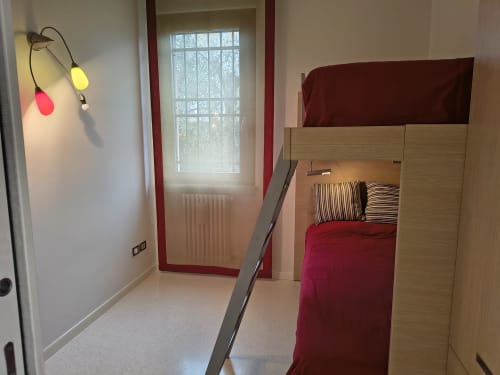 Camera in stile loft dell'hotel Prince Garda a Serniga con letto in mezzanino, cuscini a righe e moderni lampadari a sospensione