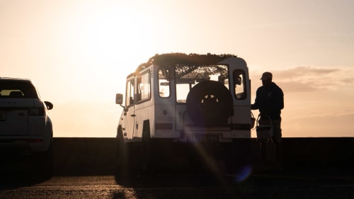 Silhouetted travelers at sunset near white safari-style vehicle at Quinta dos Lobos in Sintra