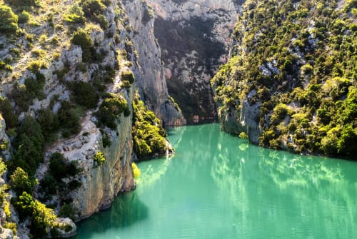 Lac turquoise entouré de falaises calcaires et de végétation verte près de Forcalquier, France