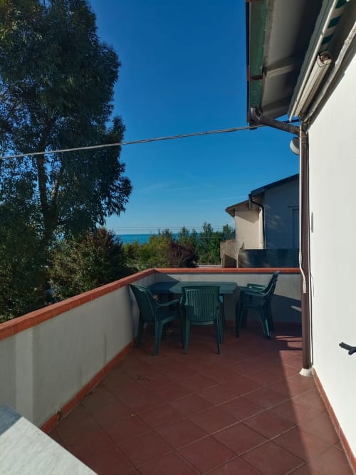 Terrazza con vista mare a Tales of Abruzzo, Atessa. Patio in piastrelle, sedie verdi, veduta della Costa dei Trabocchi.