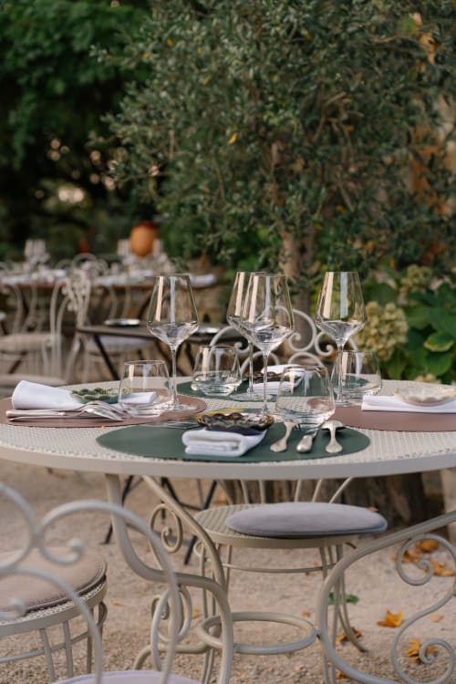 Élégant dîner en plein air au Domaine Bellavigne avec verres à vin et couverts sous une verdure luxuriante