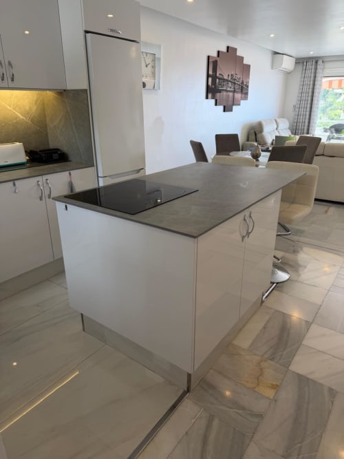 Modern open-plan kitchen and living area in 2-bed apartment near Siam Park, Tenerife with island counter, white cabinetry,