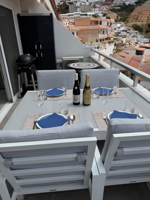 Elegant balcony dining setup at Costa Adeje apartment with sea views, set table for two with wine bottles and blue plates