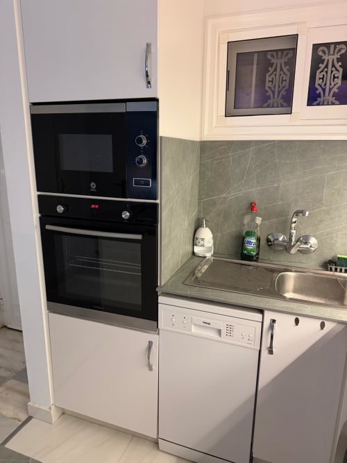 Modern kitchen in Costa Adeje apartment with built-in oven, microwave, stainless steel sink, and white cabinetry