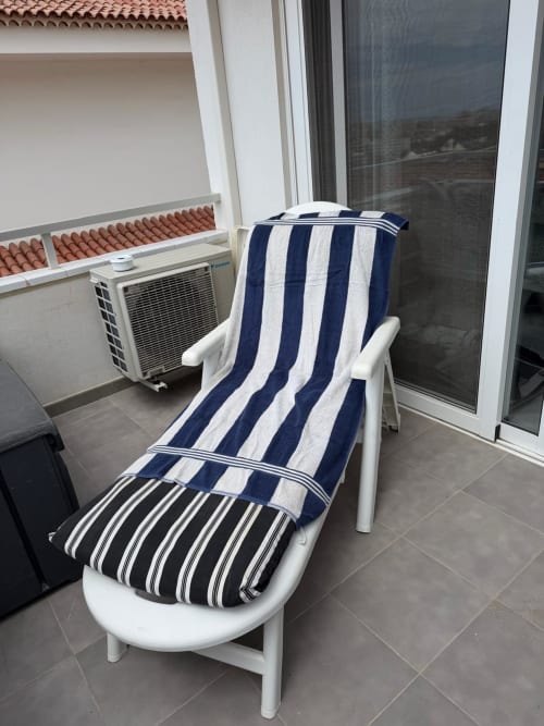 White lounge chair with navy and white striped cushion on Costa Adeje apartment balcony with sea view and AC unit