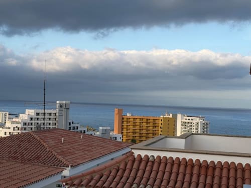 Coastal view from balcony showing terracotta roofs, colorful apartments, and Mediterranean Sea in Costa Adeje, Tenerife