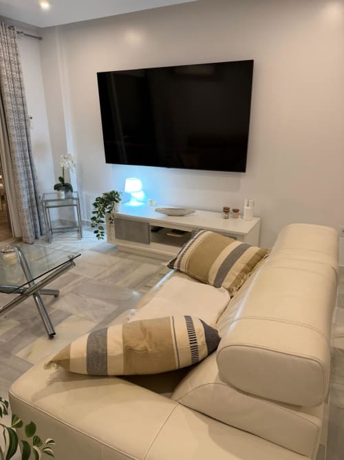 Modern living room with cream sofa, striped pillows, wall-mounted flat-screen TV, and sea-view apartment in Costa Adeje,