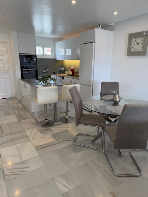 Modern open-plan kitchen and dining area in Costa Adeje apartment with white cabinetry, stainless appliances, and sea views
