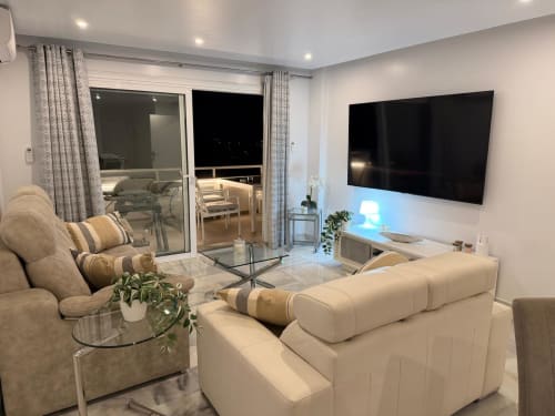 Modern living room with cream sofas, flat-screen TV, balcony overlooking Costa Adeje, Tenerife apartment near Siam Park