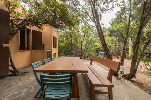 Area esterna Villa Chia con tavolo in legno e sedie blu tra gli alberi a Quartu Sant'elena