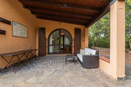 Veranda coperta di Villa Chia con portefinestre ad arco, posti a sedere confortevoli e vista sul giardino a Quartu Sant'elena