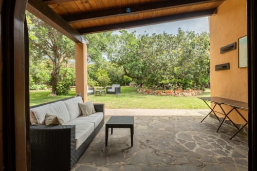 Patio ombreggiato con divano e arredo esterno che si affaccia sul giardino privato di Villa Chia, Quartu Sant'Elena