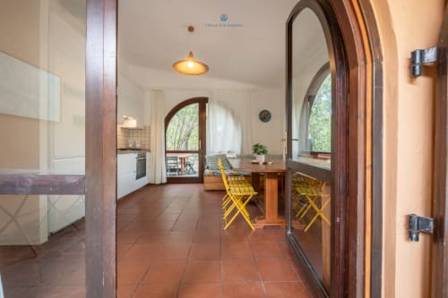 Zona pranzo della villa House Live Express con tavolo in legno, sedie gialle, vista sulla cucina e accesso al giardino a Quartu Sant'Elena
