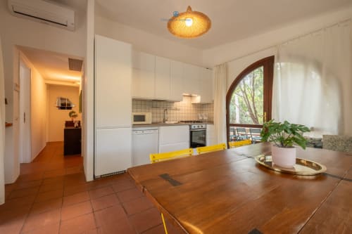 Cucina e zona pranzo moderna di Villa Chia presso House Live Express, Quartu Sant'Elena, con tavolo in legno e vista sul giardino