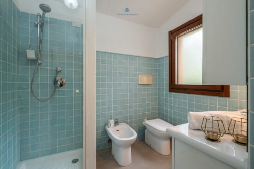 Bagno moderno turchese a Villa Chia presso House Live Express con doccia, bidet, wc e finestra sulla verdura