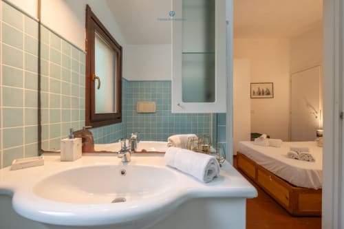 Bagno moderno con piastrelle turchesi, lavabo rotondo e specchio presso la villa House Live Express a Quartu Sant'elena, Italia