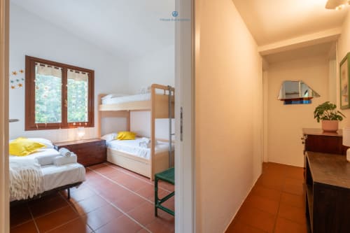 Camera luminosa di Villa Chia con letto a castello, letto singolo, pavimento in cotto e porte in legno affacciate sul giardino