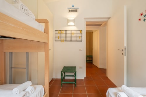 Camera Villa Chia presso House Live Express a Quartu Sant'Elena con letti a castello, sgabello verde e pavimento in cotto