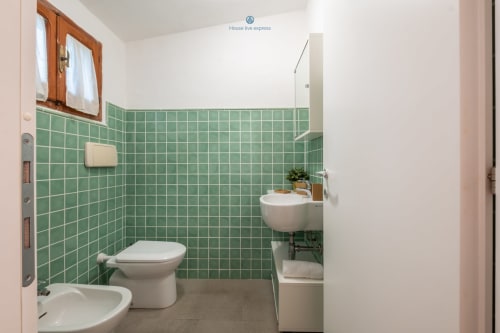 Bagno della villa House Live Express a Quartu Sant'Elena con piastrelle verdi, wc, bidet e lavabo con servizi