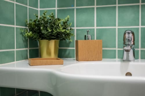 Lavabo moderno a Villa Chia con rivestimento in piastrelle verdi, pianta in vaso, accessori in legno e rubinetto cromato