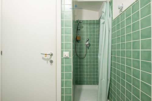 Cabina doccia con piastrelle verdi e tenda bianca nel bagno della villa House Live Express, Quartu Sant'elena