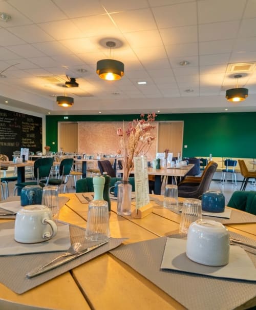Salle à manger élégante de l'hôtel La Verriaire aux murs verts, tables jaunes et décoration contemporaine à Chanverrie
