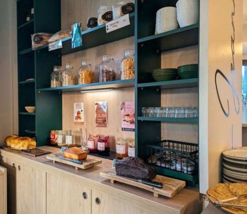 Petit-déjeuner de l'hôtel La Verriaire : viennoiseries fraîches, pain, confitures et équipements culinaires sur étagères en bois.