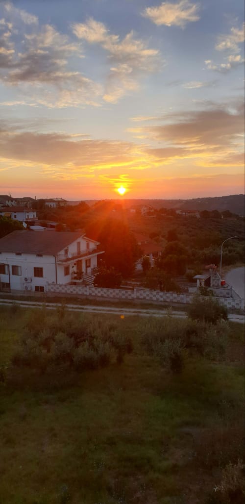 Sunset view from Tales of Abruzzo apartment in Atessa, Italy, with houses and rolling hills