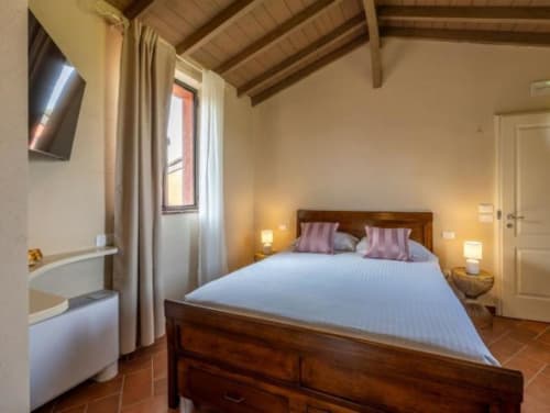 Camera Junior Suite a Corte Baruzzo Relais con letto in legno, vista giardino, TV e comfort moderni a Volta Mantovana