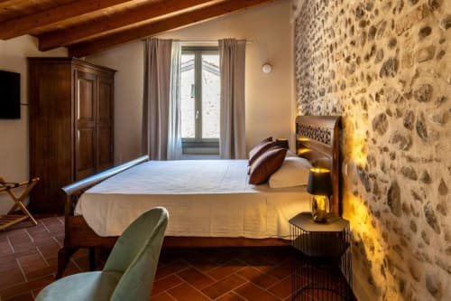 Camera rustica a Corte Baruzzo Relais con muri in pietra a vista, travi in legno e vista sul giardino a Volta Mantovana