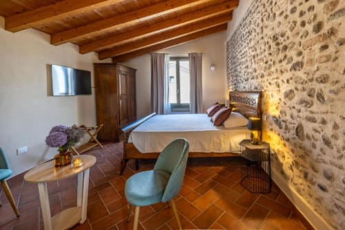 Camera Tripla Superiore a Corte Baruzzo Relais a Volta Mantovana con muri in pietra, travi in legno e vista sul giardino