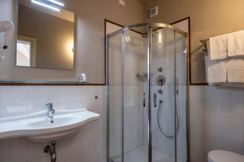 Bagno moderno presso Corte Baruzzo Relais con doccia in vetro, lavabo bianco, specchio e portasciugamani