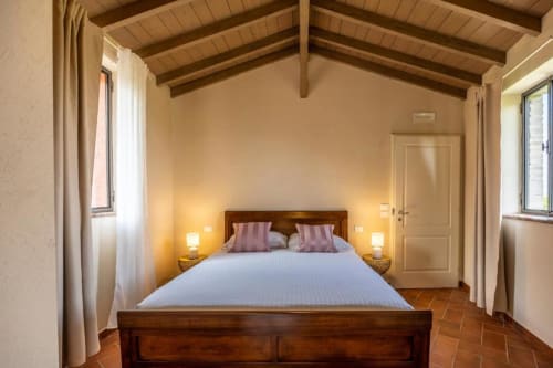 Camera Tripla Superiore presso Corte Baruzzo Relais a Volta Mantovana con letto in legno, vista sul giardino e pavimenti in cotto