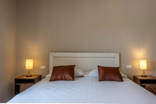 Camera comfort di Corte Baruzzo Relais con letto matrimoniale, cuscini burgundy, lampade comodino e vista sulla corte interna a Volta
