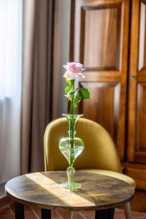 Rosa rosa singola in vaso di cristallo su tavolo in marmo nella camera dell'hotel Corte Baruzzo Relais a Volta Mantovana