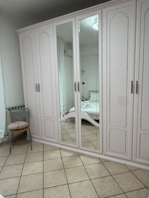 Armadio bianco con ante a specchio nella camera da letto dell'appartamento a Catania, pavimentazione in piastrelle