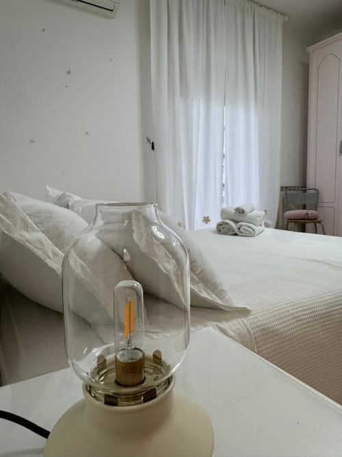 Camera da letto minimalista a Catan Apartment Nìá© a Catania con biancheria bianca, lampada lanterna e tende leggere