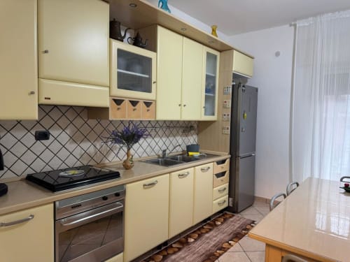 Cucina dell'Appartamento Catan Nìa© a Catania con mobili color crema, elettrodomestici in acciaio inox e rivestimento con piastrelle geometriche