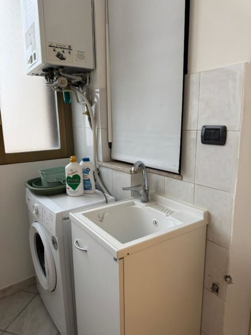 Compatta lavanderia dell'Apartment Nìa a Catania con lavatrice, lavabo e scaldabagno
