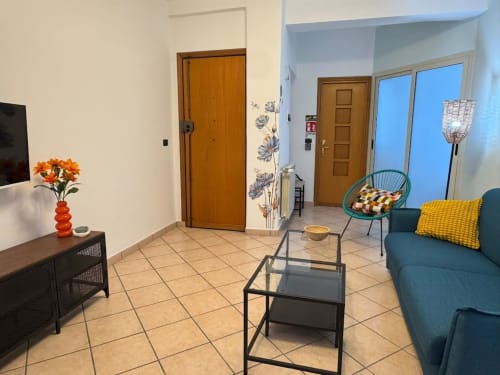 Luminoso soggiorno moderno a Catania con divano teal, porte in legno, pavimenti in piastrelle e arredamento contemporaneo