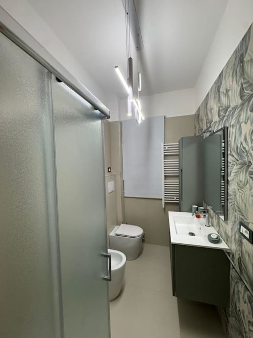 Bagno moderno dell'Appartamento Nìa a Catania con wc, lavabo, specchio, porta asciugamani e piastrelle decorate