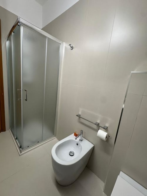 Moderno bagno dell'Appartamento Catan Niá a Catania con bidet bianco, box doccia e pareti piastrellate