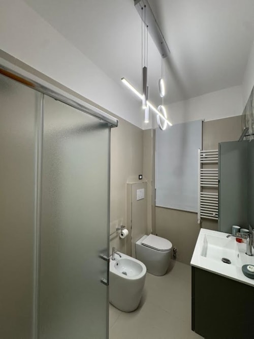 Bagno moderno dell'appartamento a Catania con doccia, bidet, wc, lavabo, scaldasalviette e luci a sospensione