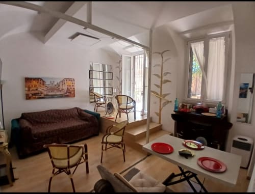 Moderno appartamento con vista sui Giardini Vaticani a Roma, zona living open-plan, divano marrone, tavolo da pranzo e vista sul giardino