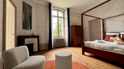 Suite élégante au Domaine du Faure avec lit à baldaquin, cheminée, parquet et vue sur le jardin